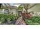 Welcoming front entrance with a brick walkway, mature palm tree, and vibrant landscaping at 7012 Treymore Ct, Sarasota, FL 34243
