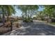 Gated community entrance with black wrought iron gates and keypad surrounded by mature landscaping and palm trees at 7012 Treymore Ct, Sarasota, FL 34243