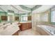Main bathroom featuring dual sinks, vanity, soaking tub, and glass shower at 7012 Treymore Ct, Sarasota, FL 34243