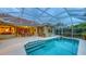 This outdoor pool features a screened enclosure, tile roof, and a covered patio with a dining set, perfect for entertaining at 7012 Treymore Ct, Sarasota, FL 34243