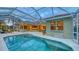A sparkling swimming pool is enclosed by a screen, and surrounded by a patio, with a tiled roof and lush landscaping at 7012 Treymore Ct, Sarasota, FL 34243