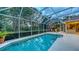 Screened pool features clear blue water, privacy landscaping, and nearby seating area for enjoying the Florida outdoors at 7012 Treymore Ct, Sarasota, FL 34243
