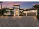 Elegant home exterior with manicured landscaping, paver driveway, and three-car garage with sunset sky at 7211 Pasadena Gln, Lakewood Ranch, FL 34202
