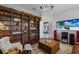 Charming living room featuring a custom bookshelf with library ladder, TV, and hardwood flooring at 7211 Pasadena Gln, Lakewood Ranch, FL 34202