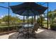 Outdoor dining area with a table, chairs, and an umbrella overlooking the golf course at 7211 Pasadena Gln, Lakewood Ranch, FL 34202
