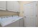 Bright laundry room featuring white cabinets, a washer and dryer, and a nearby door at 7424 Sea Island Ln, Bradenton, FL 34201