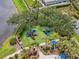 Overhead shot of a vibrant playground with multiple play structures and lush landscaping near a tranquil pond at 7424 Sea Island Ln, Bradenton, FL 34201