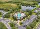 Aerial view of the community pool and lounge area near a pond with surrounding lush greenery at 7424 Sea Island Ln, Bradenton, FL 34201
