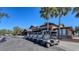 Clubhouse with a neat row of golf carts parked outside, framed by palm trees and lush landscaping against a clear blue sky at 7717 Us Open Loop, Lakewood Ranch, FL 34202