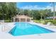 Relax by the pristine community pool, featuring a covered lounging area, surrounded by lush greenery and serene landscaping at 7717 Us Open Loop, Lakewood Ranch, FL 34202