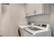 Bright laundry room with white washer and dryer and above-machine cabinets at 7717 Us Open Loop, Lakewood Ranch, FL 34202