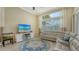 Cozy living room boasts hardwood floors, large windows, neutral paint, and an adjacent TV console at 7717 Us Open Loop, Lakewood Ranch, FL 34202