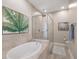 A luxurious bathroom featuring a soaking tub, glass enclosed shower, and neutral colored tile at 7840 34Th Ave W # 303, Bradenton, FL 34209