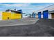 Property featuring a bright yellow gate and modern blue accents, complete with palm trees and ample parking space at 8100 Ciboney Ct # 10, Sarasota, FL 34240