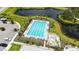Aerial view of a community pool with lounge chairs, palm trees, and lush landscaping next to a serene pond at 10254 Morning Mist Ln, Sarasota, FL 34241