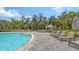 Inviting poolside lounge area with comfortable chairs, umbrellas, cabana, and lush tropical landscaping at 10254 Morning Mist Ln, Sarasota, FL 34241