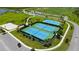 A beautiful aerial view of community tennis and basketball courts surrounded by lush green spaces and palm trees at 10254 Morning Mist Ln, Sarasota, FL 34241