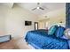 Bright bedroom with a TV, ceiling fan, mirror, and a comfortable-looking blue bed and leather bench seat at 1064 N Tamiami Trl # 1125, Sarasota, FL 34236