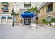 Building entrance with palm trees, planters, and a covered blue awning at 1064 N Tamiami Trl # 1125, Sarasota, FL 34236