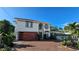 Front exterior showcasing a modern home with a tile roof, a brick driveway, and beautiful landscaping at 1240 Solitude Ln, Sarasota, FL 34242