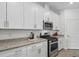 Modern kitchen featuring granite countertops, stainless steel appliances, and white cabinetry at 15716 Barefoot Beach Dr, Bradenton, FL 34211