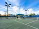 Well-maintained tennis courts with blue canopies, lighting, and lush landscaping under a bright blue sky at 17612 Northwood St, Lakewood Ranch, FL 34202