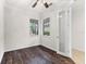 Bedroom with dark wood floors, two windows, ceiling fan and glass paneled door at 19023 Mangieri St, Venice, FL 34293