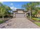 Charming home featuring a paver driveway and two-car garage, complemented by lush palm trees and well-maintained landscaping at 19023 Mangieri St, Venice, FL 34293