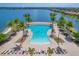Stunning aerial view of a community pool featuring palm trees, lounge areas, and a lake backdrop at 201 Vinadio Blvd, Nokomis, FL 34275