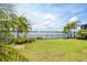 The backyard features a lush lawn, tropical foliage, a black fence, and a scenic lake view with a fountain at 201 Vinadio Blvd, Nokomis, FL 34275