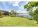 This backyard has a lush lawn, tropical foliage, a black fence, and a scenic lake view at 201 Vinadio Blvd, Nokomis, FL 34275
