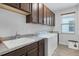 This laundry room has overhead cabinets, a sink with a light countertop, a washing machine, and a dryer at 201 Vinadio Blvd, Nokomis, FL 34275