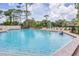 Large community pool surrounded by lounge chairs and lush greenery on a sunny day at 3617 Yellow Pine Ct # 144, Sarasota, FL 34238