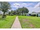 Well-manicured front yard with a sidewalk leading through the lush lawn and mature trees at 3721 Somerville Dr # 1513, Sarasota, FL 34232