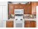 Well-lit kitchen featuring granite countertops, wooden cabinets, and white appliances at 4440 Fairways Blvd # 310, Bradenton, FL 34209