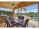 View of the shaded patio area with stylish patio furniture, ceiling fan and a view of the pool and lake at 4531 Useppa Dr, Bradenton, FL 34203