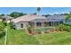 A view of the screened in pool surrounded by landscaping, tropical foliage, and a lush green lawn at 4531 Useppa Dr, Bradenton, FL 34203