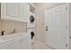 Well-organized laundry room featuring a utility sink, white cabinetry, and a stacked washer and dryer for efficiency at 4727 Starboard Dr, Bradenton, FL 34208