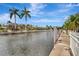 Waterfront property featuring a beautiful canal, seawall, and tropical landscaping under a blue sky at 4727 Starboard Dr, Bradenton, FL 34208