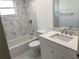 This bathroom features a shower and tub with beautiful marble tile, vanity with sink, toilet, and window at 481 Saturn Ave, Sarasota, FL 34243