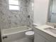 Updated bathroom featuring marble tile around the tub and shower, a new vanity with sink, and a toilet at 481 Saturn Ave, Sarasota, FL 34243