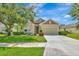 Inviting front exterior featuring lush lawn, mature trees, and a charming façade at 5005 Torrey Pines Run, Bradenton, FL 34211