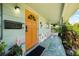 Inviting front porch with a vibrant orange door, colorful brick accents, and lush greenery at 5317 14Th S Ave, Gulfport, FL 33707