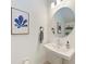 Elegant half bathroom featuring a modern vanity, round mirror, and tasteful blue botanical artwork at 5711 Archipelago St, Nokomis, FL 34275