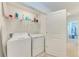 A tidy laundry room features a washer and dryer, shelving, and convenient access to other parts of the house at 5711 Archipelago St, Nokomis, FL 34275