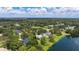 An aerial view showcases residences in a verdant neighborhood with mature trees and a tranquil lake at 601 136Th St E Ct, Bradenton, FL 34212