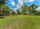 Lush backyard with green grass and mature trees leading to a pond at 601 136Th St E Ct, Bradenton, FL 34212