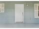 Close-up of the side door with white siding, matching shutters, and an exterior light fixture at 601 136Th St E Ct, Bradenton, FL 34212