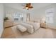 Staged primary bedroom showcases neutral colors, bedside tables, a seating bench and two windows at 6266 Buckingham St, Sarasota, FL 34238