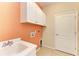 A utility sink with orange wall and white door provide laundry conveniences at 6516 Palm Leaf Ct, Sarasota, FL 34243